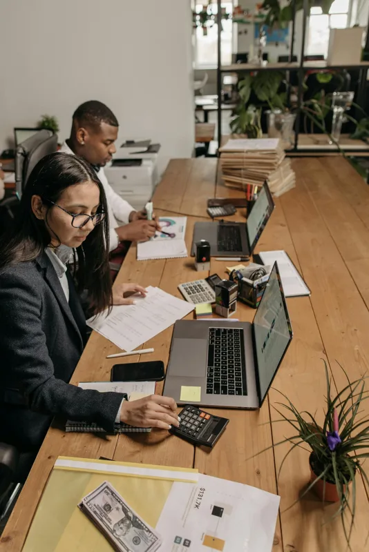 Two accountants and a small business owner reviewing financial reports together at an office desk